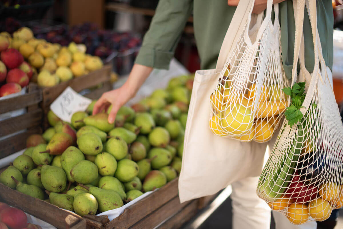 women shopping at farmers market with reusable totes