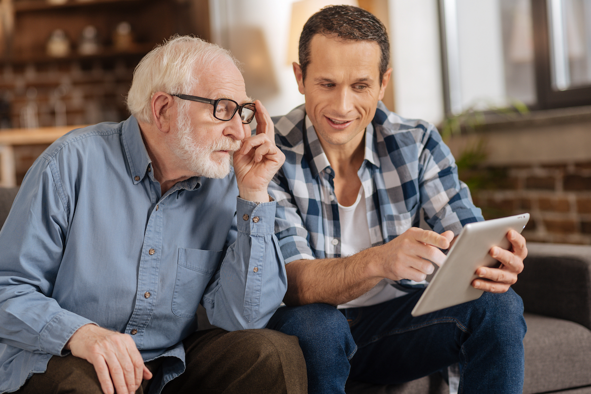 Senior Man and Son Look at Tablet_Uplands Village