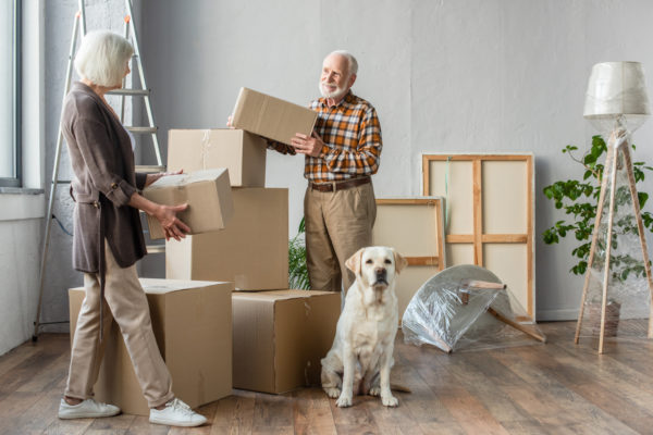 Senior Couple Moving Boxes with Dog_Uplands Village