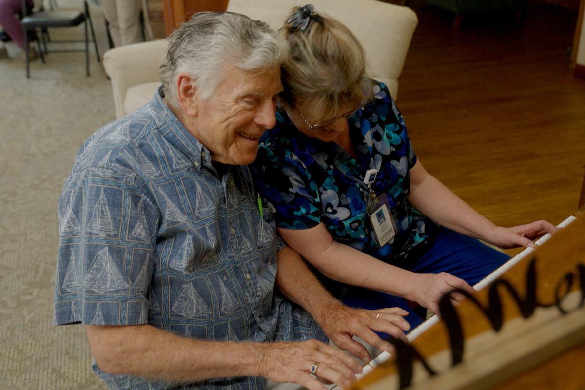 Senior and Caregiver Playing Piano_Uplands Village