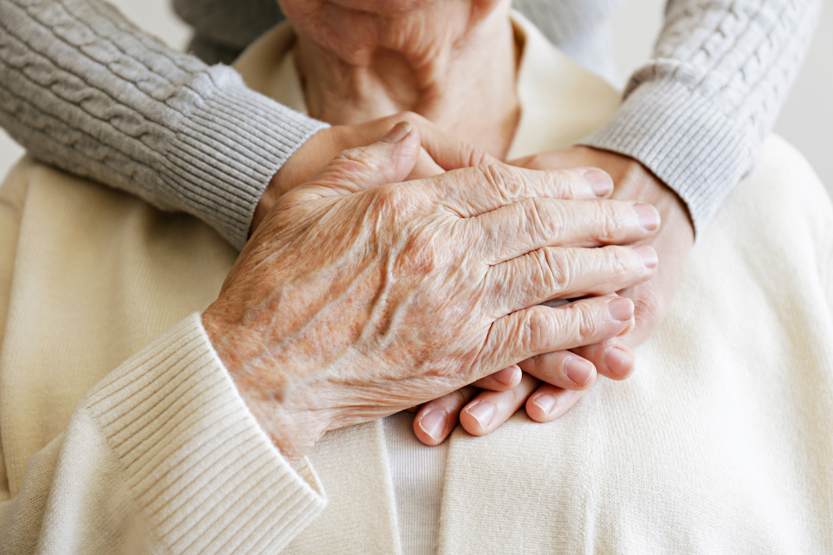 Caregiver Arms Wrapped Around Senior Woman_Uplands Village