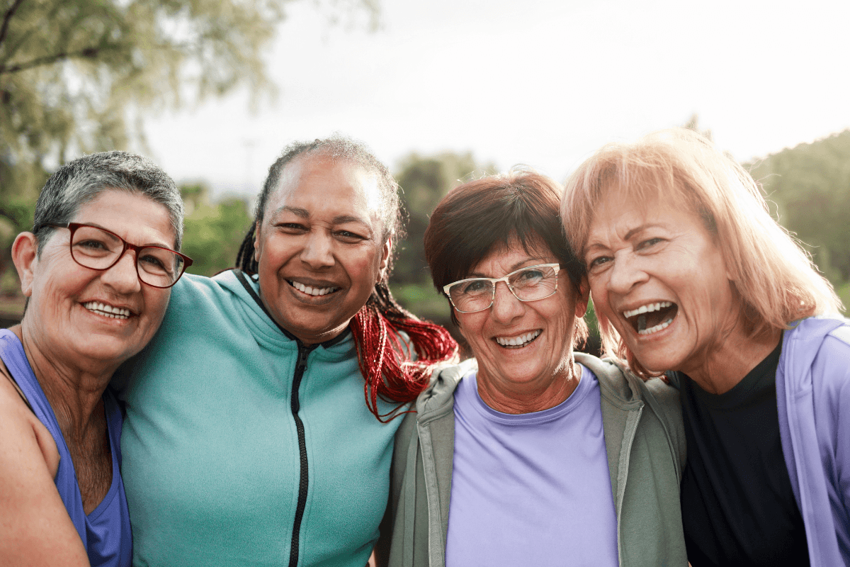Diverse elderly people having fun hugging each other outside after sport training.