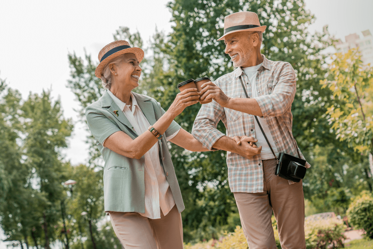 A joyful elderly couple smiling lovingly at one another as they enjoy a leisurely outdoor date.